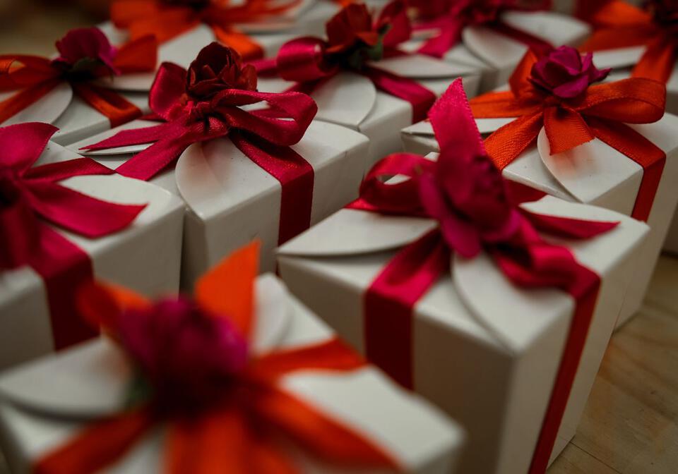 Une image remplie de cadeaux emballés avec du papier blanc et de gros rubans rouge autour de chaque cadeau.